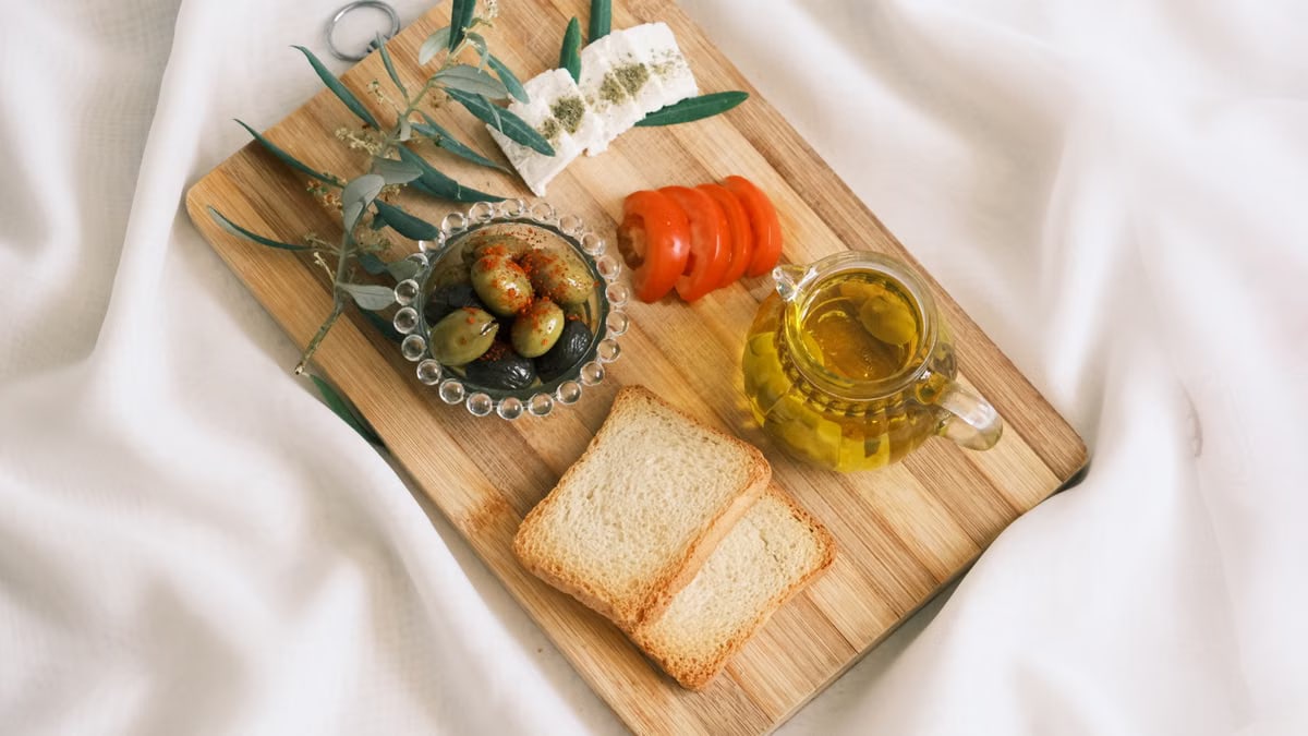 A delicious assortment of olives, cheese, tomatoes, and bread arranged on a wooden board.